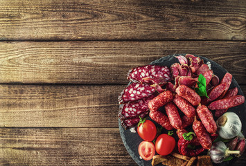 Food tray with delicious salami, pieces of sliced ham, sausage, tomatoes, salad and vegetable.