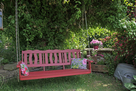 Rote Schaukelbank in einem Garten