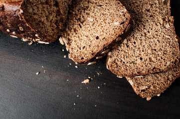 delicious fresh baked slices of bread with sunflower seeds on a dark table, horizontal image