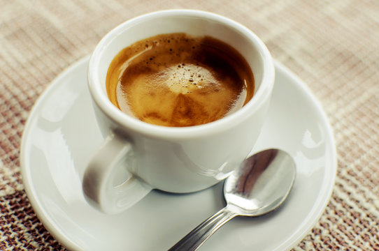 A cup of freshly prepared espresso coffee with foam on fabric, horizontal image