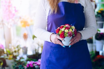 Young woman owner of florist shop holding a composition on beauty flower