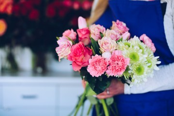 Young woman owner of florist shop making a composition of pink roses.