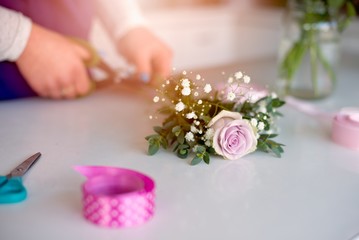 Woman owner of florist shop preparing bouquet of pink roses