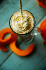 Pumpkin smoothie, spice latte with whipped cream on top on a turquoise wooden background. copy space