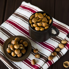 hazelnuts in a clay mug with shell around on a wooden table and striped towel