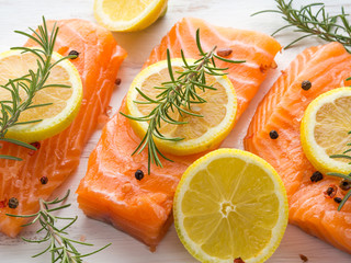 Raw salmon pieces on wooden board with herbs, salt and spices