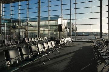 Piece of airport interior in the early morning. Glass windows, seats, architectural details. Concept of travel and air transport. Selective focus.