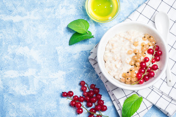 Overnight oatmeal porridge with berries on light blue background. Healthy breakfast. Top view, space for text. 