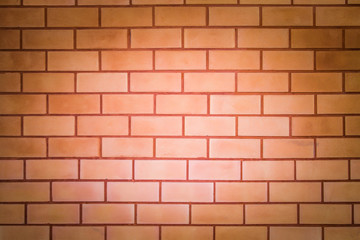 Brick wall with orange stain, light in the middle for background or wallpaper.
