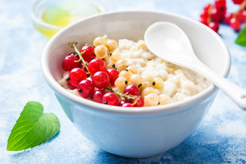 Overnight oatmeal porridge with berries on light blue background. Healthy breakfast. Selective focus, space for text.