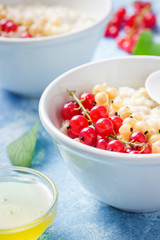 Healthy oatmeal porridge with berries on light blue background. Selective focus, Space for text.