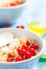 Healthy morning oatmeal with berries and coconut milk on light blue background. Selective focus, close up.