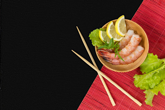 Shrimp on a wooden plate with wooden chopsticks