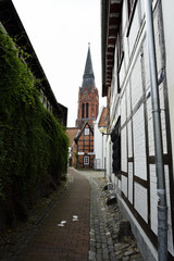 Fototapeta na wymiar Schmale Gasse mit Blick auf die Kirche in Nienburg