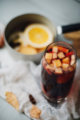 Hot mulled wine in a glass with orange slices, anise and cinnamon sticks, star cookies on vintage wood table. Christmas or winter warming drink with recipe ingredients around