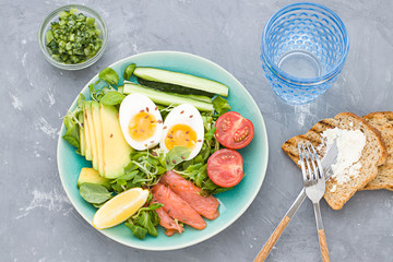 Healthy salad with avocado, corn salad, smoky salmon, eggs and tomatoes for breakfast. Top view
