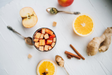 Hot mulled wine or grog cooking for new year celebration with oranges and spices ingredients on light background flat lay