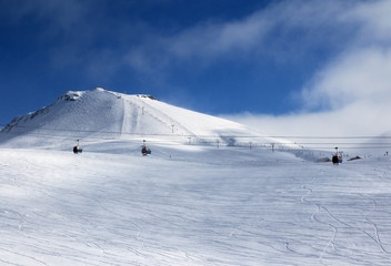 Fototapeta na wymiar Gondola and chair lifts on ski resort at winter evening with snowfall