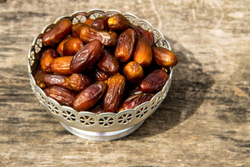 Dates fruit on a silver bowl on wooden table. The Muslim feast of the holy month of Ramadan Kareem