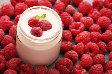 Raspberries yogurt in jar on wooden table