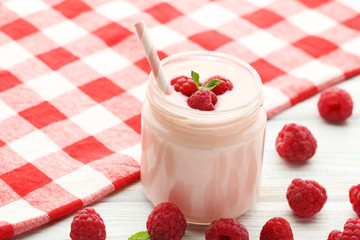 Raspberries yogurt in jar on wooden table