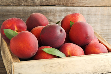 Sweet nectarines in crate on grey wooden table