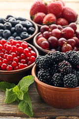 Ripe and sweet berries in bowls on wooden table