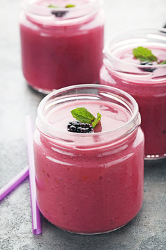 Blackberries yogurt in bottles on grey wooden table
