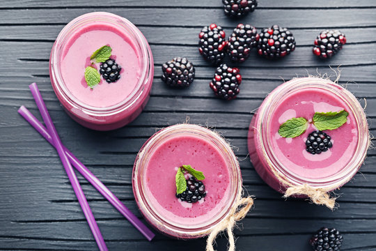 Blackberries yogurt in bottles on black cutting board