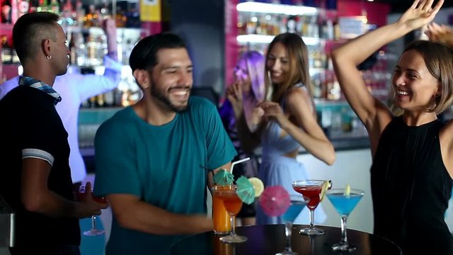 Female with man are dancing and drinking cocktail on the party in bar.
