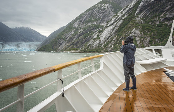 a tourist taking photo of a gracier on a cruise ship in Alaska