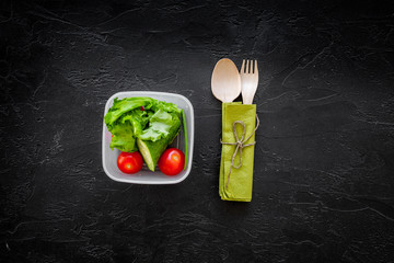 Healthy meal in containers. Summer salad with tomato and cucumber on black background top view