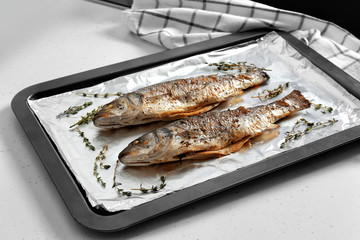 Baking tray with tasty fish on kitchen table