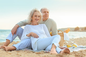 Happy senior couple having picnic on sea beach