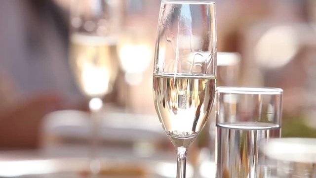 The waiter pours champagne in wineglass, in a restaurant, The waiter pours champagne in crystal glasses, Restaurant interior, buffet table, Waiter in white gloves, close-up