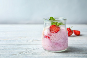 Tasty quinoa with strawberry in jar on wooden table