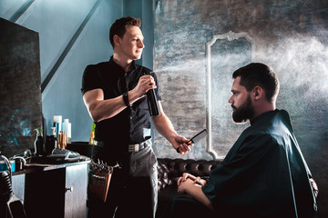 Handsome bearded male client getting haircut by hairdresser at the barbershop. A professional job in salon