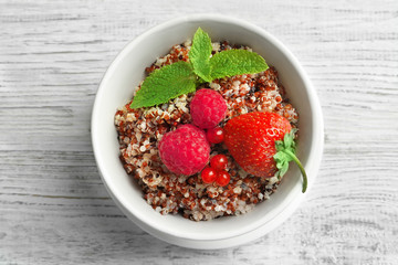 Tasty quinoa with berries in bowl on wooden table