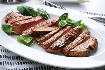 Plate with delicious steak on table in cafe, closeup