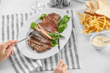 Woman eating delicious grilled steak in restaurant