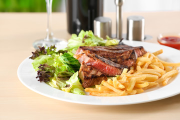 Plate with delicious steak and garnish on table in cafe