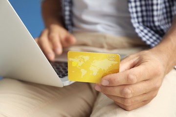 Man holding credit card while using laptop