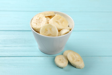 Bowl with yummy banana slices on wooden background