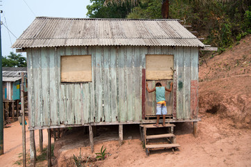 Fototapeta na wymiar Hut on piles and boy in village on mud background