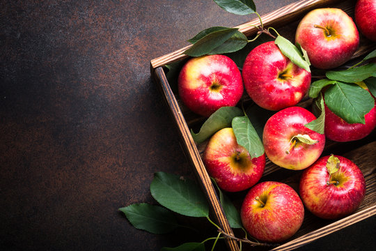 Red apples in wooden box. Top view with copy space on rusty background.