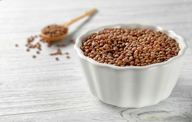 Bowl with brown lentils on wooden table