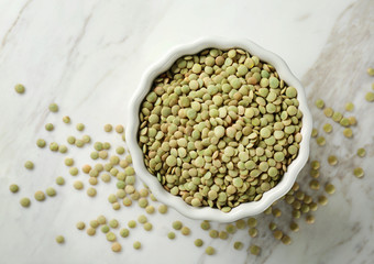 Bowl with green lentils on wooden table