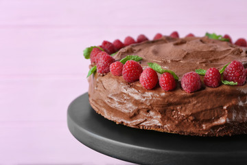 Dessert stand with delicious chocolate cake on pink background