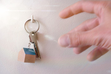 Hands catching keys on a hook on the wall