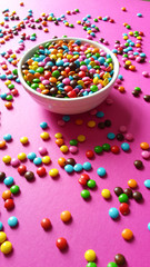colorful confetti scattered on pink background (vertical photo)